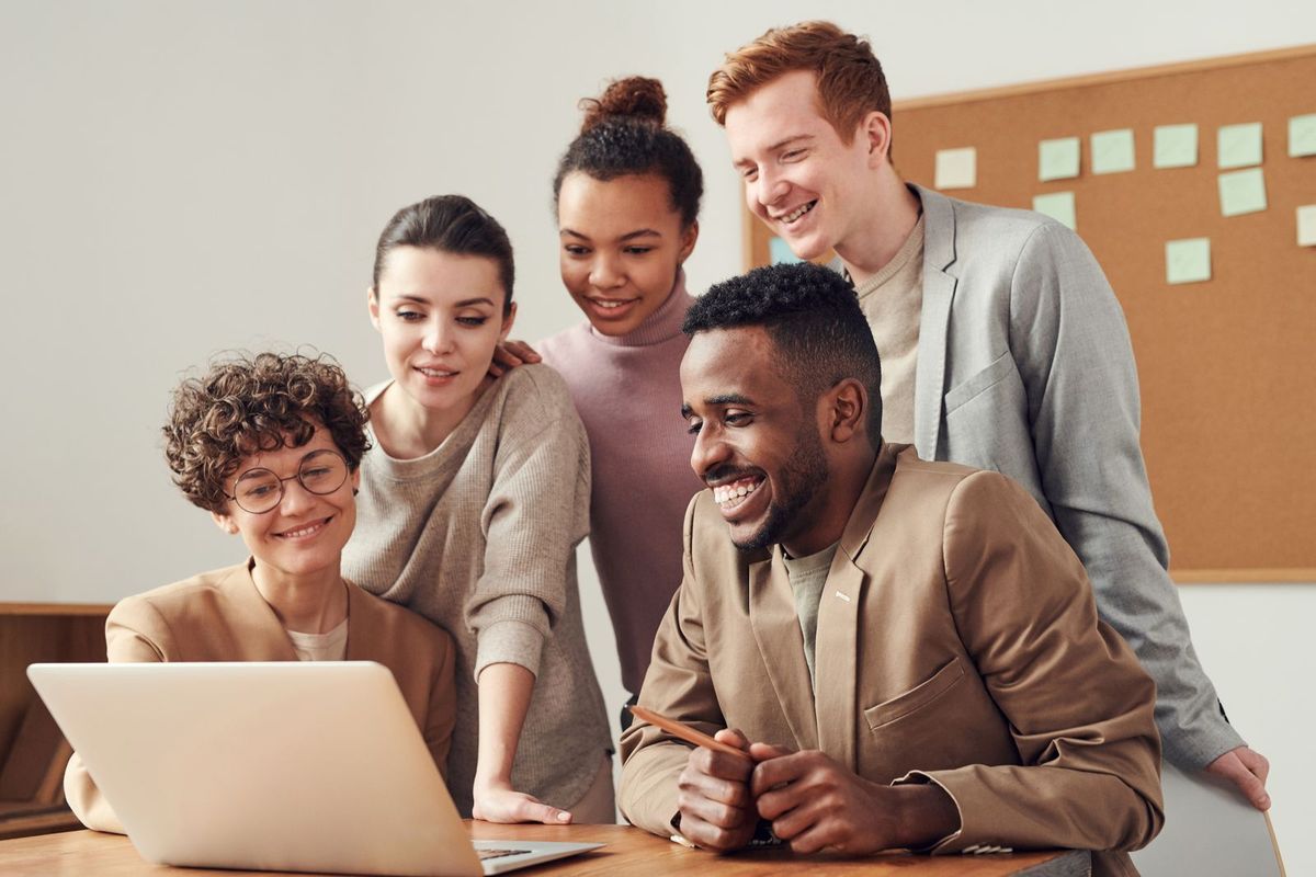 Colleagues gathered around a laptop, smiling