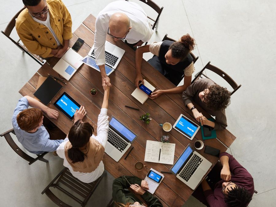 A team at a table covered with laptops and tablets, seen from above