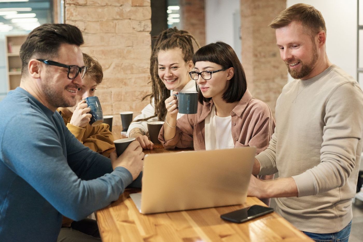 A small team around a laptop, laughing over coffee